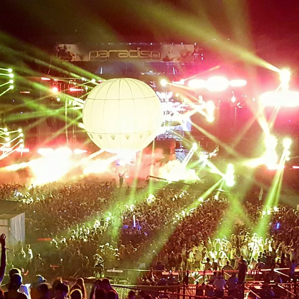 A large nighttime concert crowd beneath dramatic stage lighting